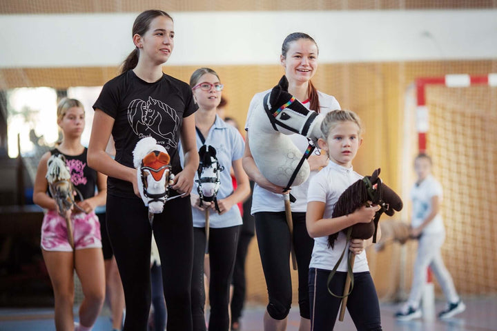 Otroci in najstniki s Hobby Horse konji med dogodkom Hobby Horsing v dvorani