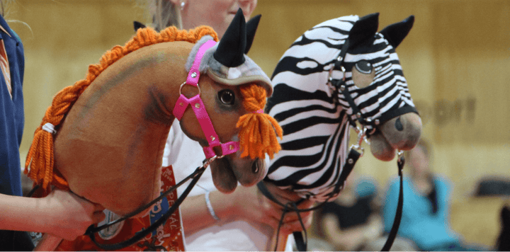 Dva Hobby Horse konja s spletenima grivama, eden rjav z oranžno prejo, drugi z zebrastim vzorcem