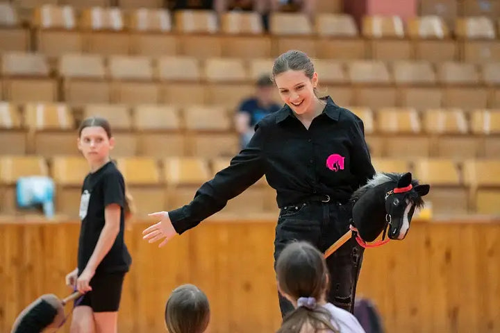 Predstavitev športa Hobby Horsing v športni dvorani, ženska drži črnega Hobby Horse konja