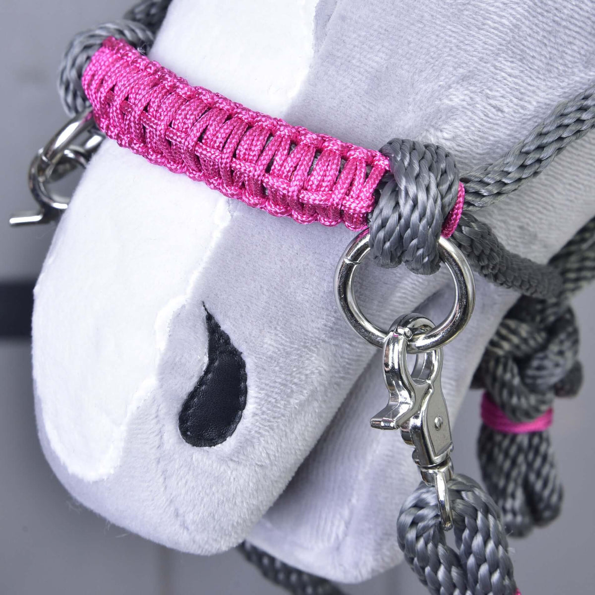 Close-up of the pink wrapped noseband with silver ring and snap hook on the grey rope halter of a Hobby Horse