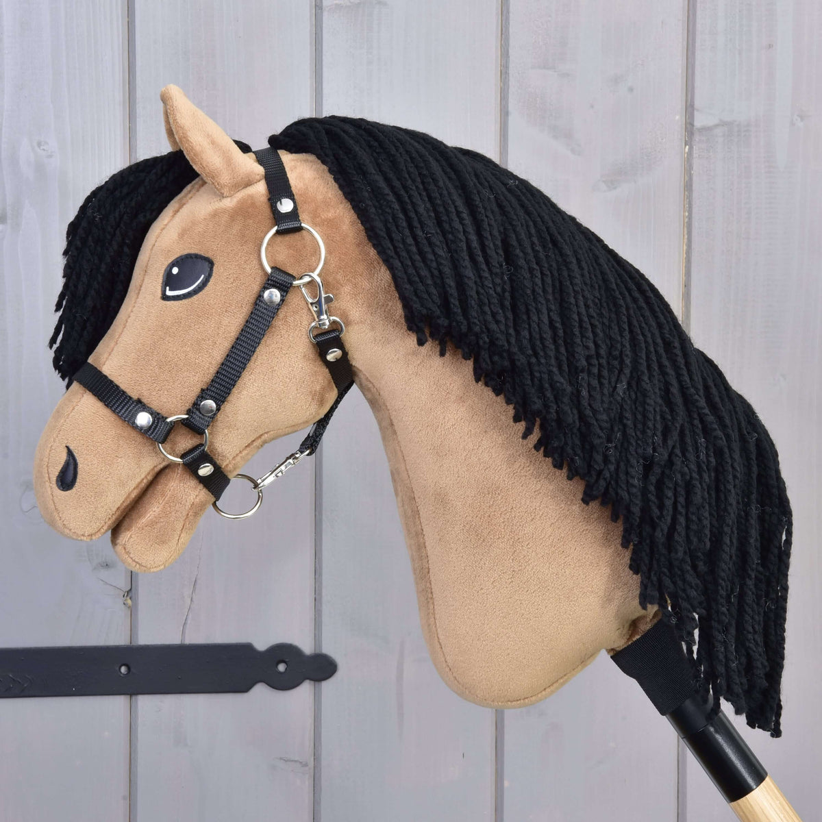Hobby Horse Samantha in profile with black halter, silver rings and snap hook, and a long black yarn mane