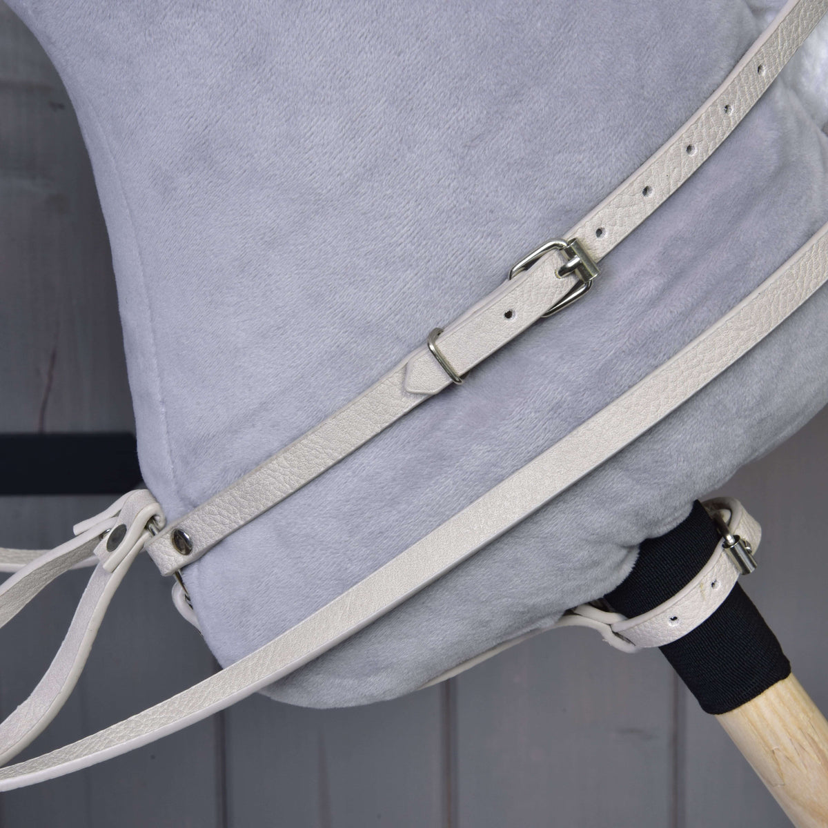 Bližnji posnetek smetanastega vratnega jermena martingala z zaponko in vajeti na vratu sivega Hobby Horse konja