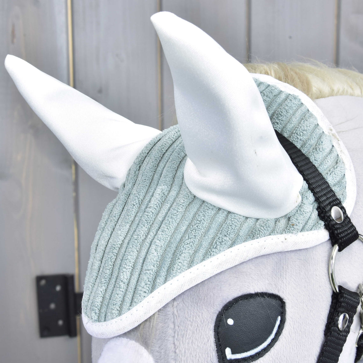 Close-up of the Manchester Little Green ear bonnet with white satin ears and white binding on sage green corduroy
