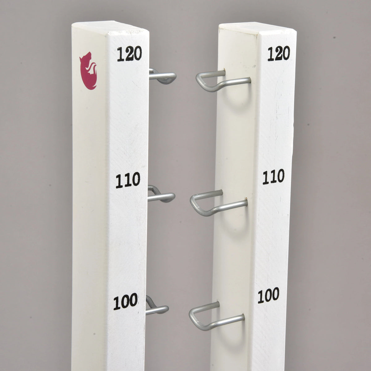 Vrhova obeh visokih stojal z oznakami 100, 110 in 120 cm, kovinskimi kaveljčki in majhnim roza logotipom konja
