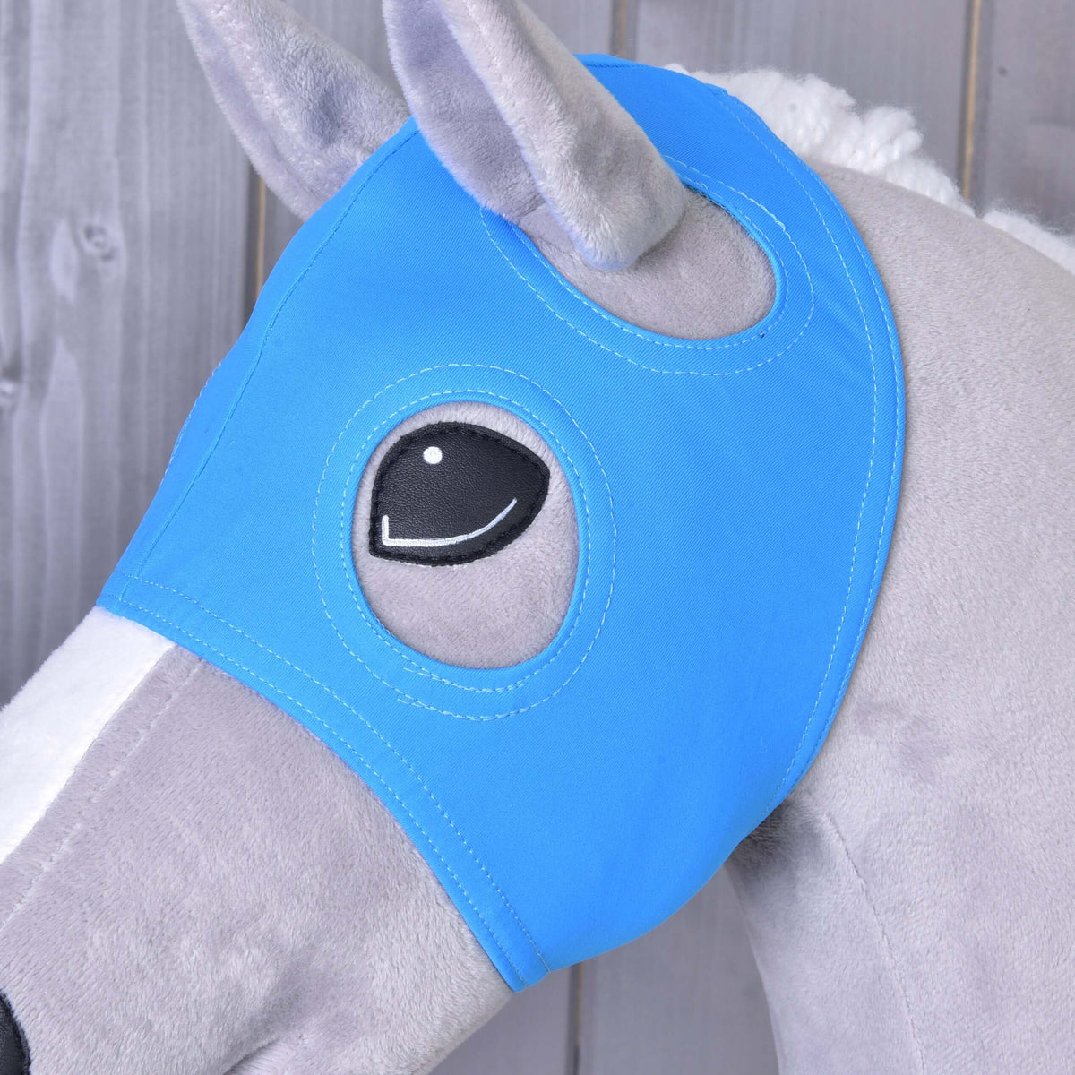 Bližnji posnetek maske brez ušes Sky na sivem Hobby Horse konju, odprtini obkrožata plišasto uho in črno oko