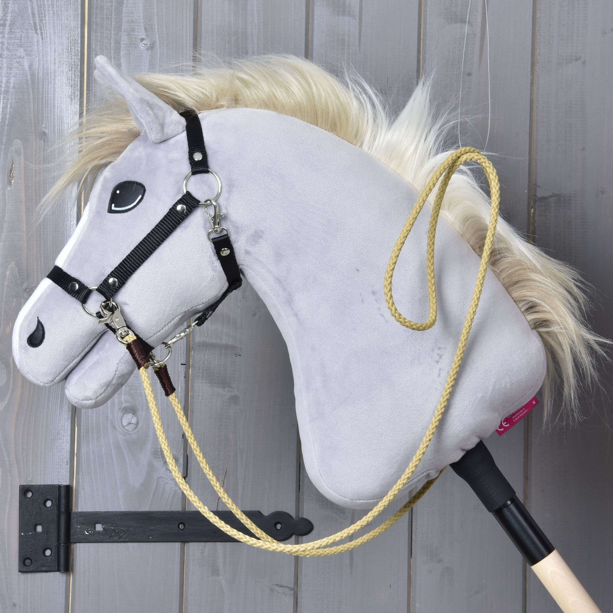 Siv Hobby Horse konj s črno oglavko in pripetimi western vajetmi Dakota peščene barve, prevešenimi čez vrat