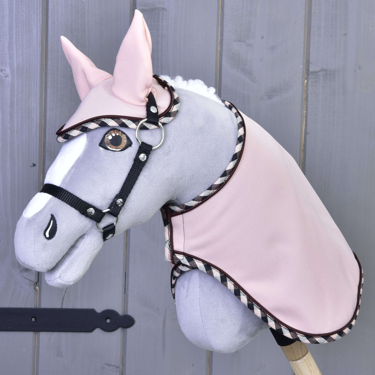 Grey Hobby Horse with amber eyes and black halter wearing Set Abby, the pale pink blanket and ear bonnet with checked trim