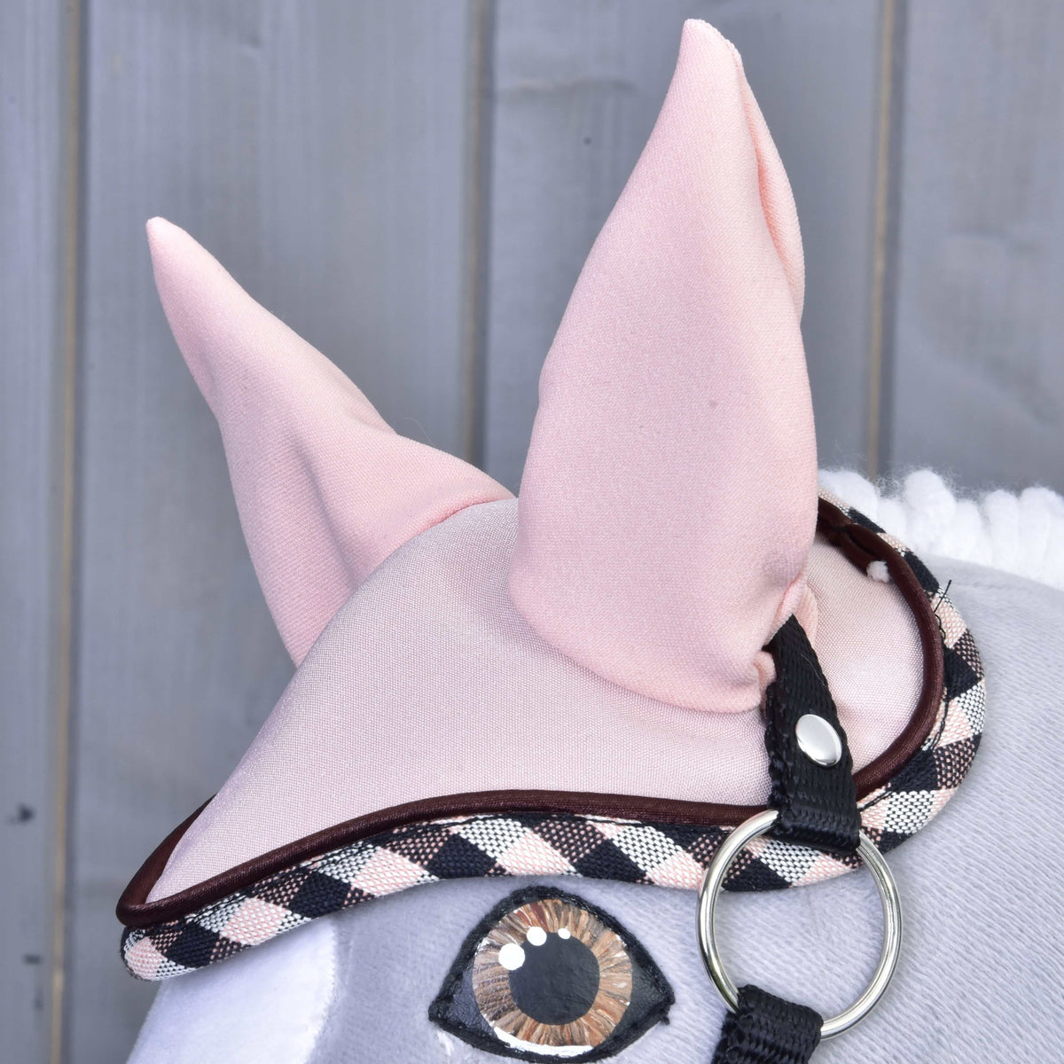Set Abby ear bonnet on a grey Hobby Horse, with tall pink ears, brown piping and black, white and pink checked edging