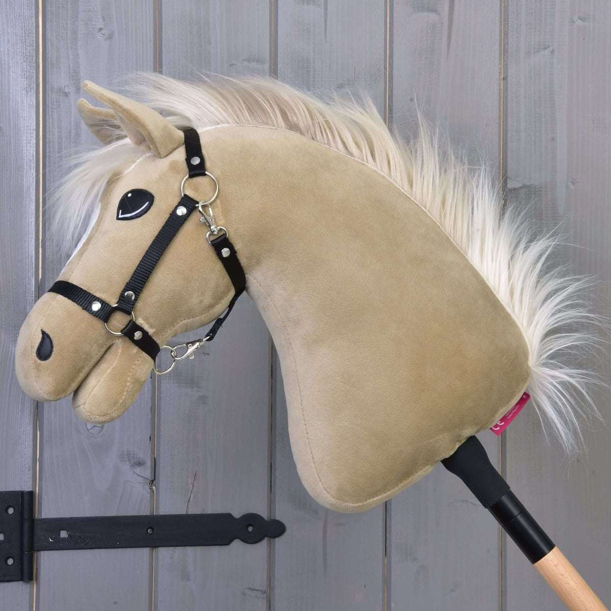 Hobby Horse Dancing Lady with Black Halter from the side, head lowered, long fluffy cream mane and wooden stick
