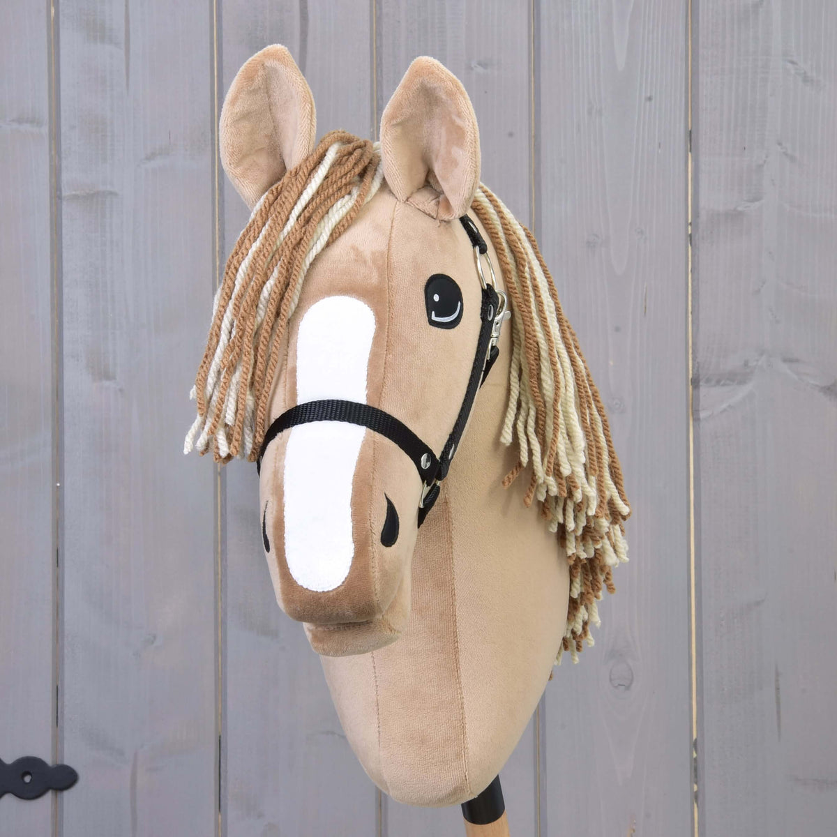 Hobby Horse Bren with Black Halter from the front, wide white blaze and a two-tone brown and cream yarn forelock