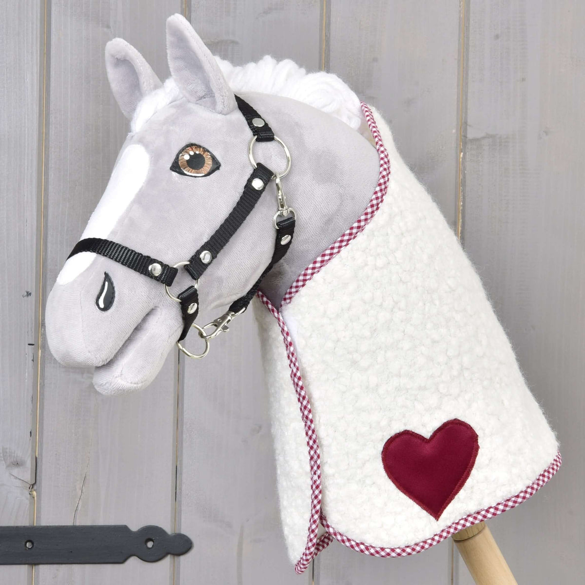 Light grey Hobby Horse in a black halter wearing the Blanket cube red with burgundy heart and checked trim