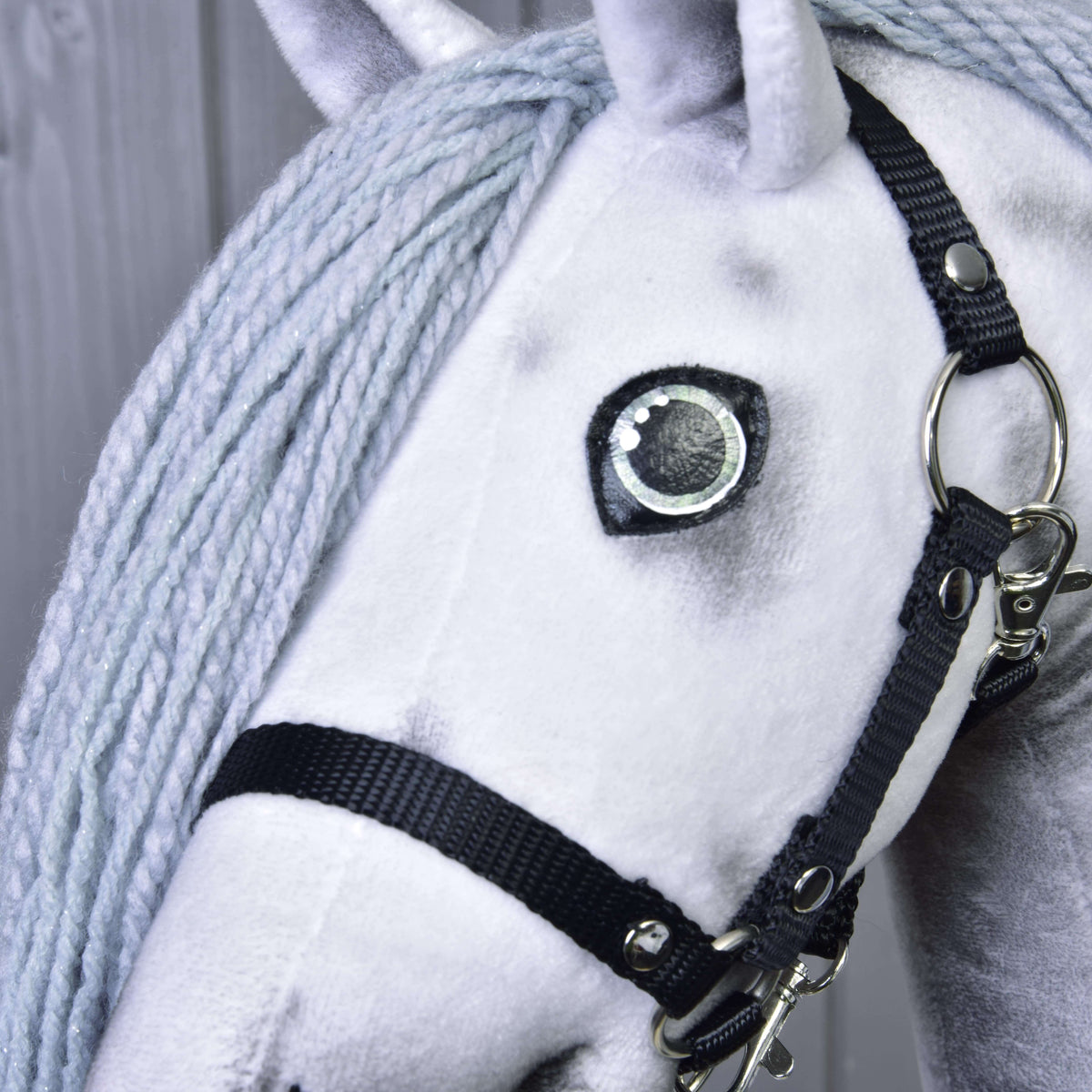 Bližnji posnetek očesa in črne oglavke Hobby Horse samoroga Silver, svetlo siva griva iz preje s finimi srebrnimi bleščicami