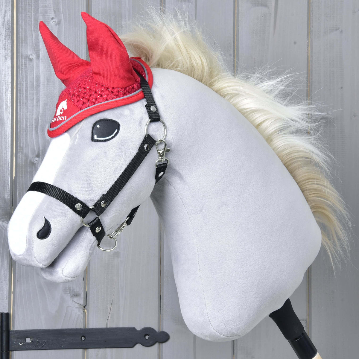 Siv Hobby Horse konj z blond grivo in črno oglavko nosi živo rdeče kvačkane naušnike Red Sport