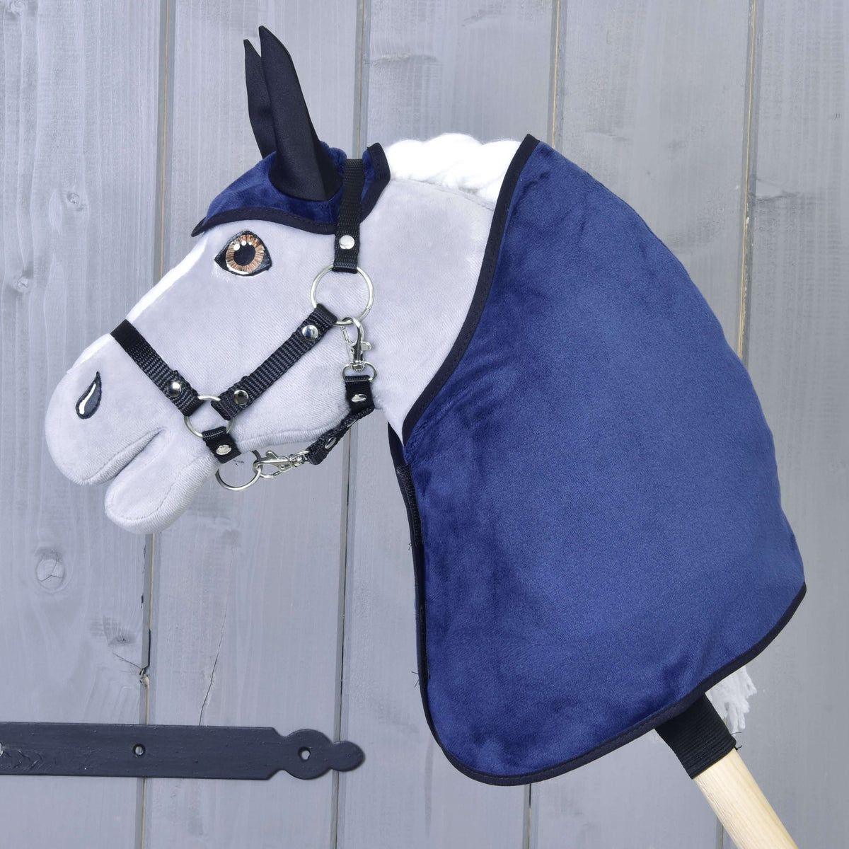 Siv Hobby Horse konj z rjavimi očmi v črni oglavki nosi temno modro žametasto pregrinjalo in naušnike