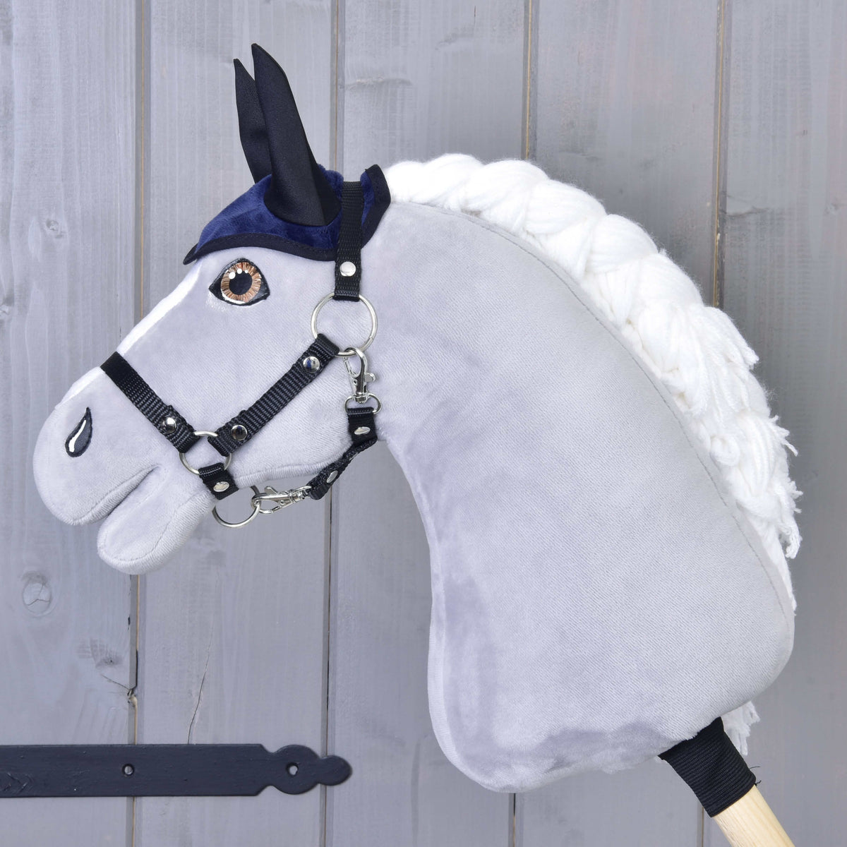 Siv Hobby Horse konj v črni oglavki nosi samo temno modre naušnike s črnimi ušesnimi deli