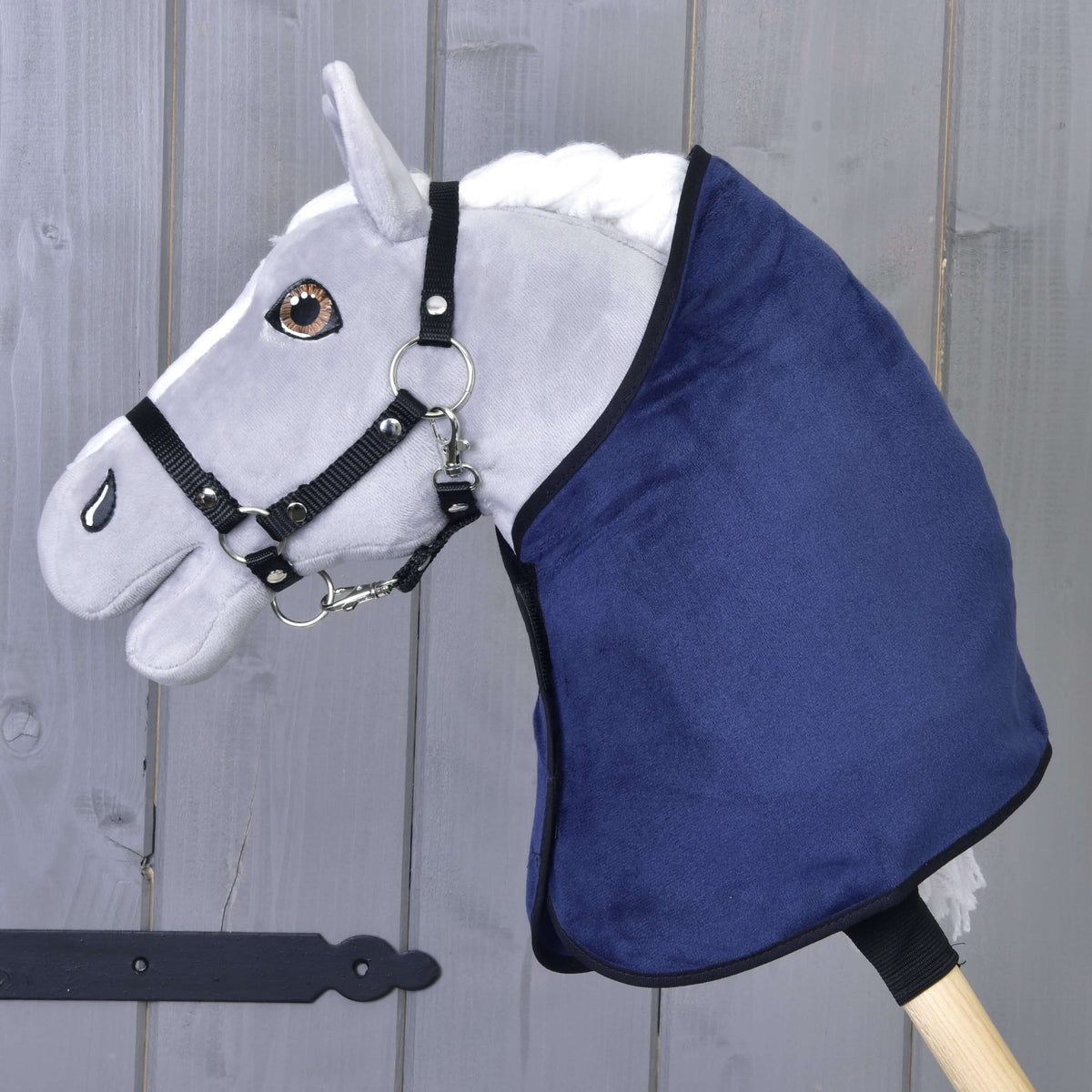 Siv Hobby Horse konj v črni oglavki nosi samo temno modro žametasto pregrinjalo s črno obrobo