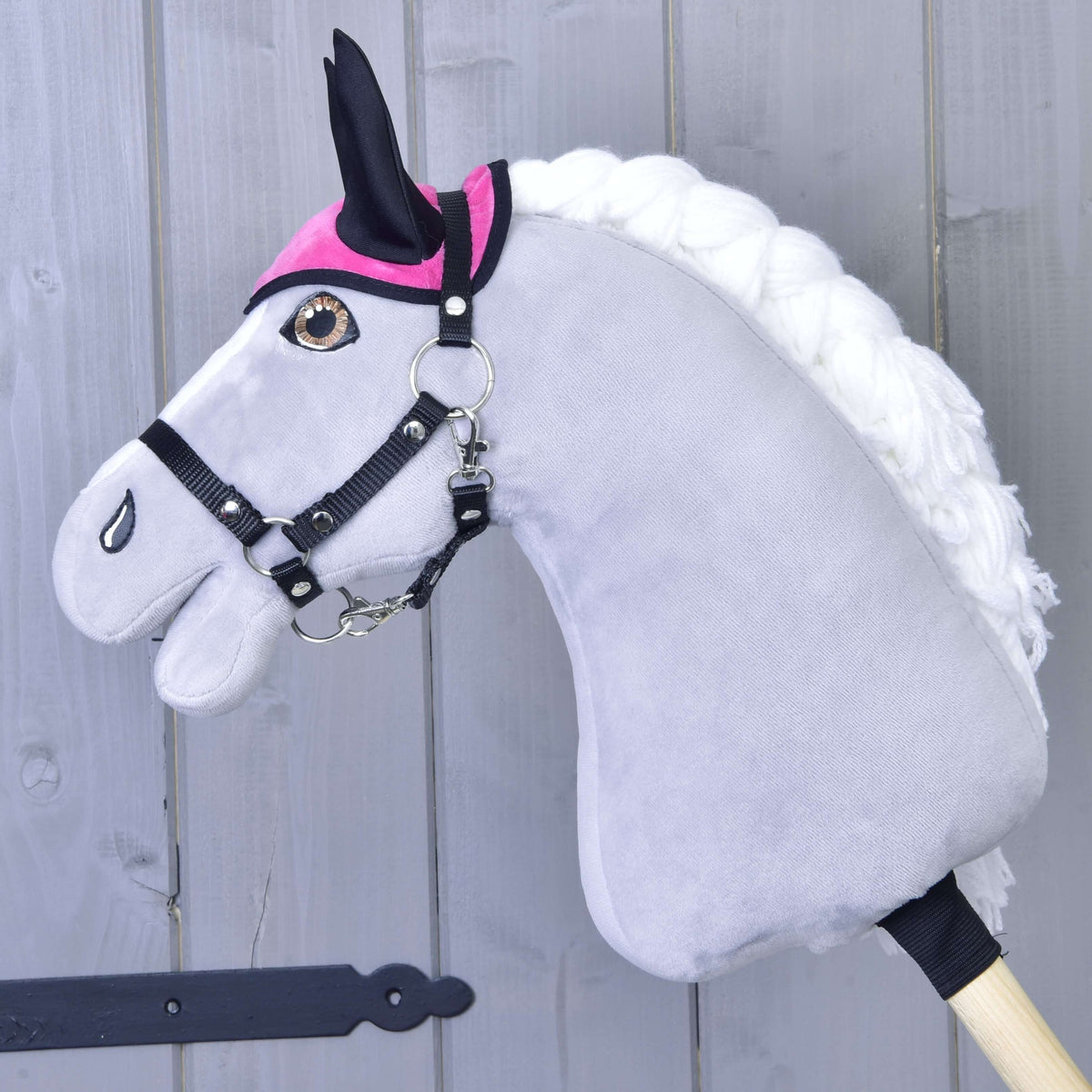 Siv Hobby Horse konj v črni oglavki nosi samo živo roza naušnike s črnimi ušesnimi deli