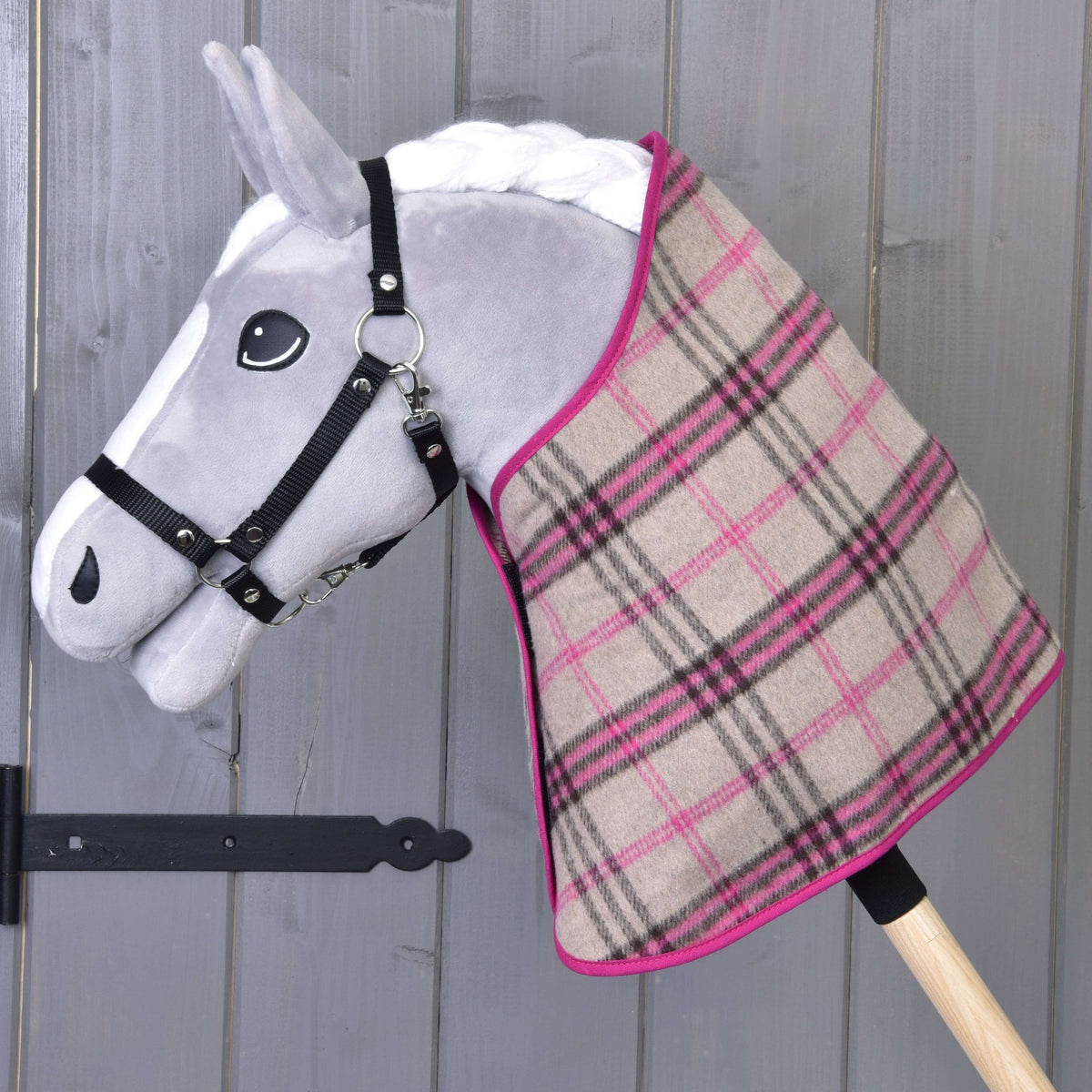 Siv Hobby Horse konj v črni oglavki nosi samo bež-roza karirasto pregrinjalo z roza obrobo