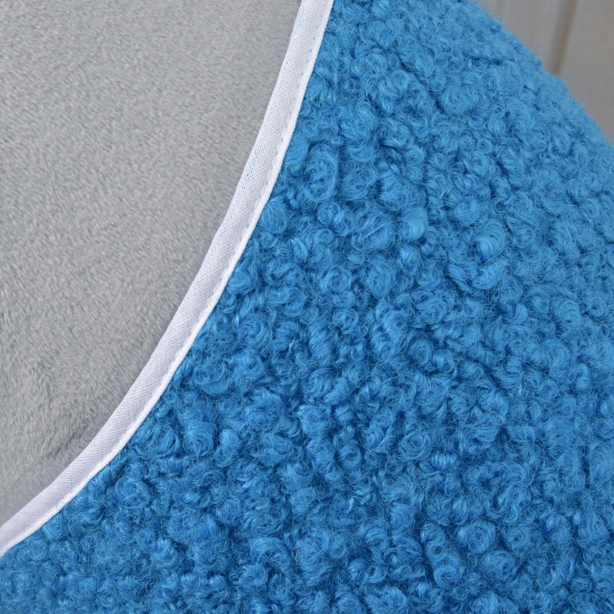 Close-up of the curly blue fleece texture and white binding at the neckline of the blanket