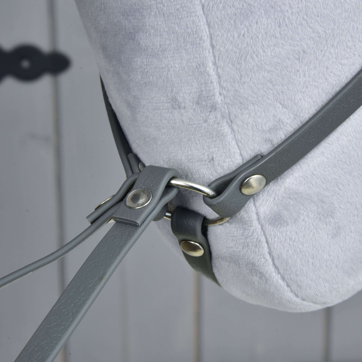Bližnji posnetek pod plišastim vratom, kjer se vratni jermen martingala pri srebrnem obročku z zakovicami stika s krakoma