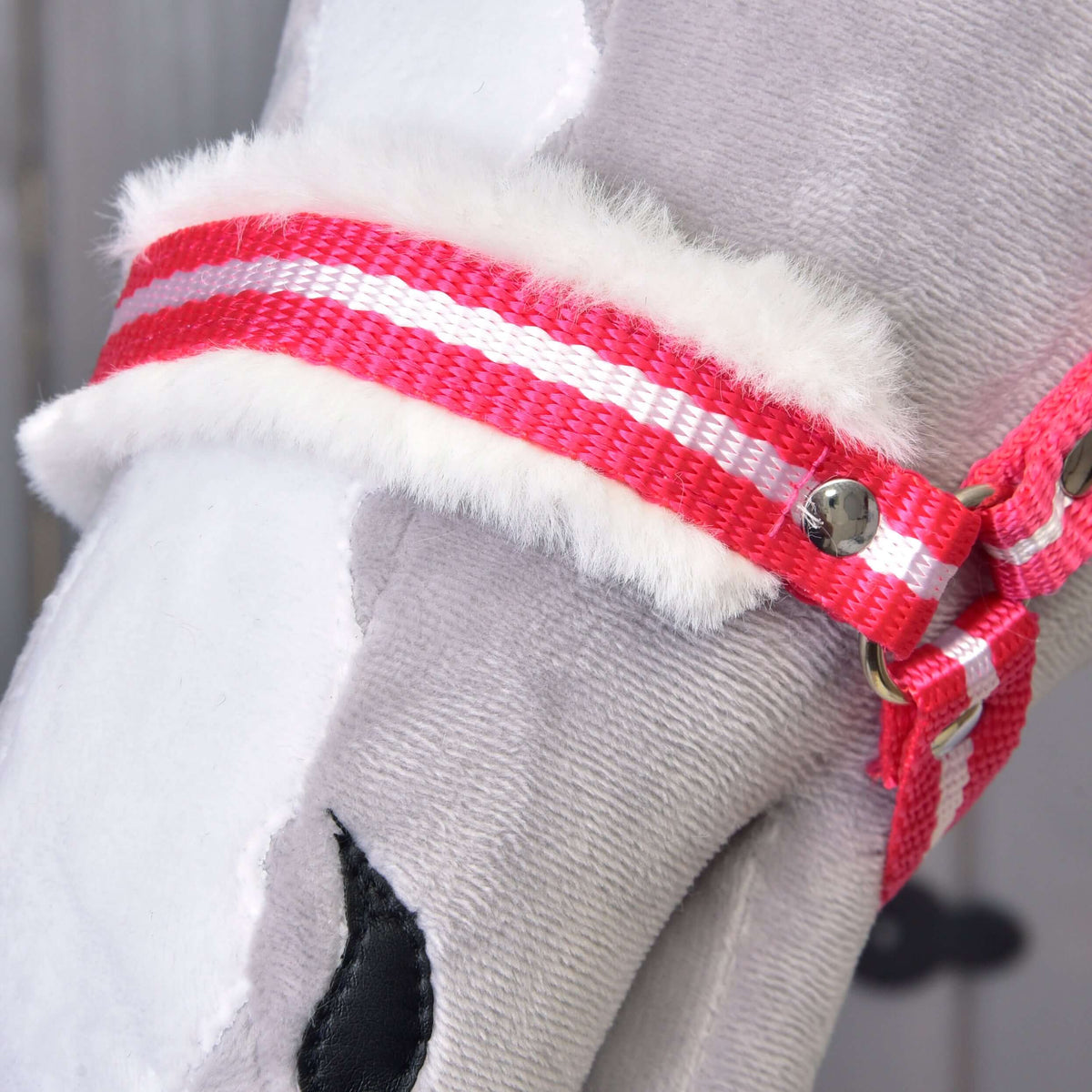 Close-up of the red and white striped noseband with soft white fur padding on a grey plush Hobby Horse