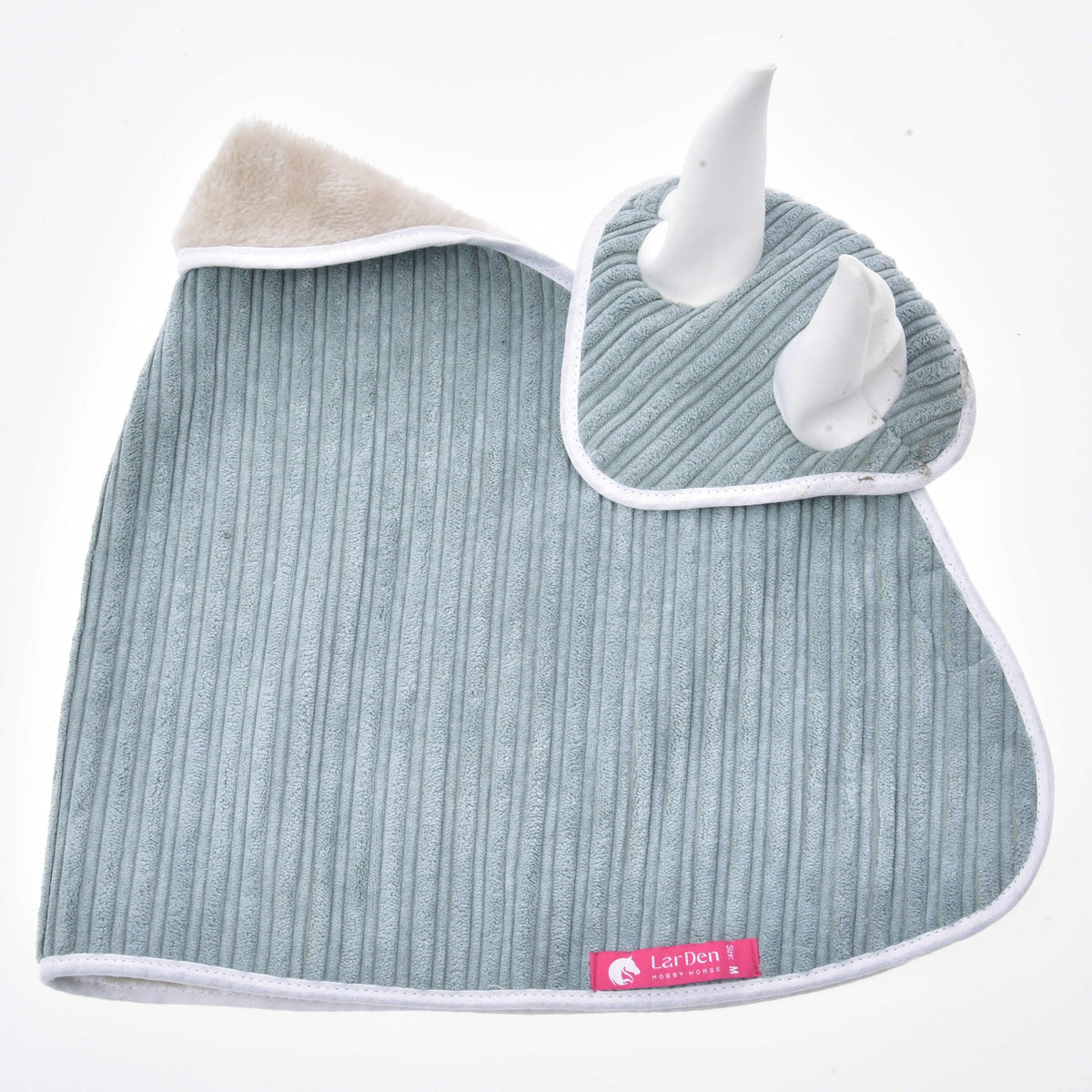 Sage green corduroy blanket and ear bonnet laid flat, cream fleece at the neck and a pink LarDen label at the hem