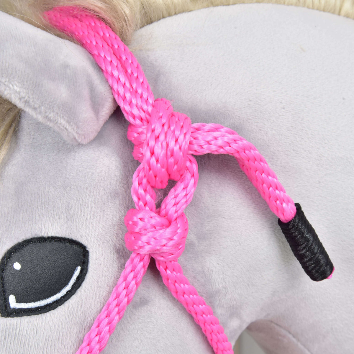 Close-up of the pink rope halter's knots by the ear and the black whipped rope end on a grey plush head