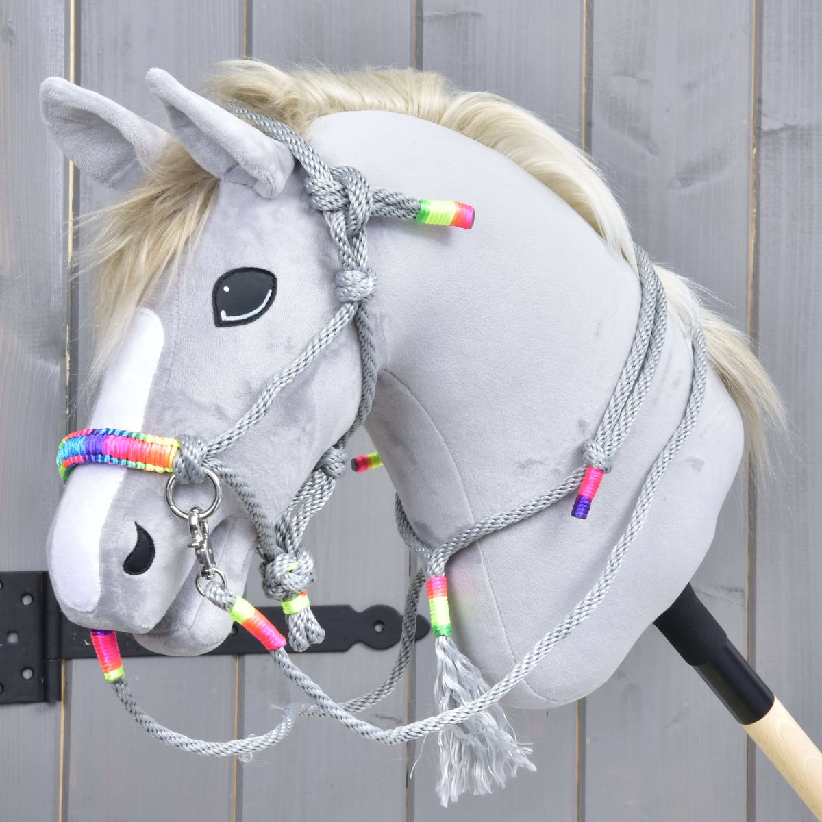 Grey Hobby Horse wearing Rope set Manhattan: grey rope halter with a rainbow noseband, reins and a neck ring with tassel
