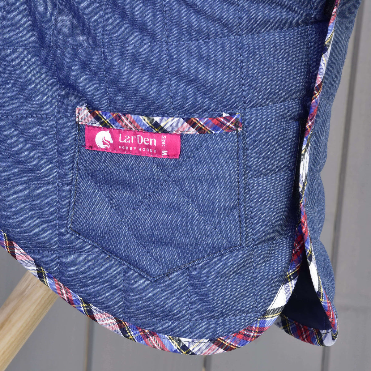 Detajl žepa na pregrinjalu Hobby Horse kompleta Jeans z roza etiketo LarDen, prešitjem v vzorcu rombov in rdeče-modro karirasto obrobo