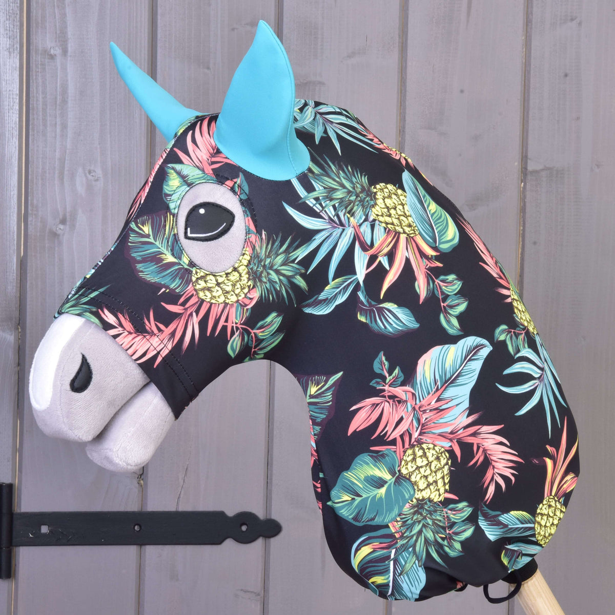 Hobby Horse zaščitna obleka Pineapple (Lycra) znamke LarDen, nameščena čez glavo: ananasi in listi na črni podlagi, turkizna ušesa