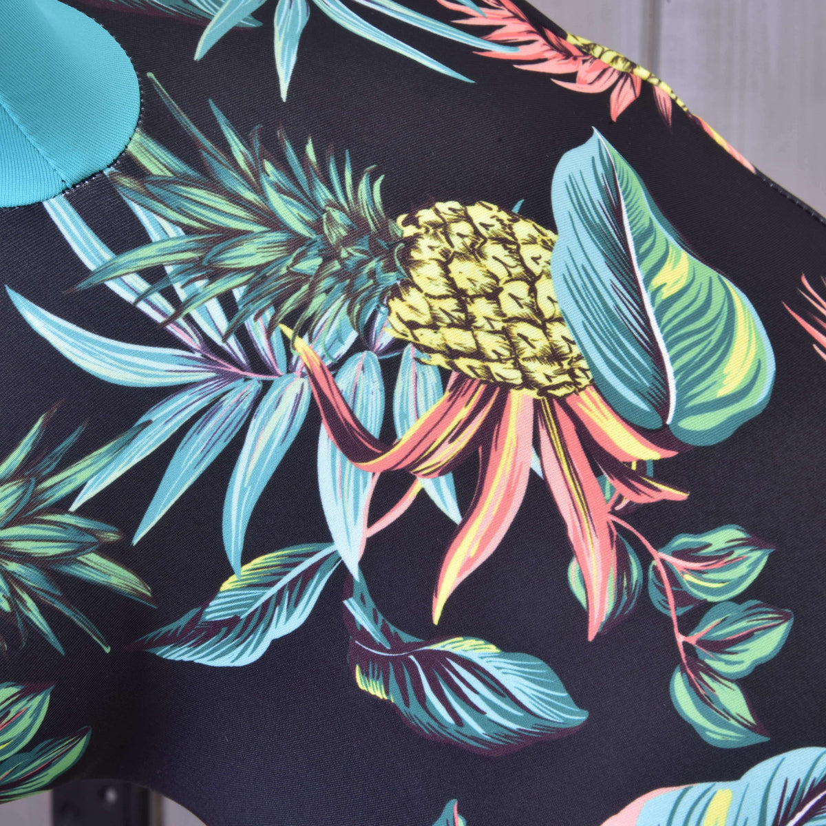Podrobnost potiska Hobby Horse zaščitne obleke Pineapple: rumen ananas, turkizni in koralni listi na črnem materialu Lycra
