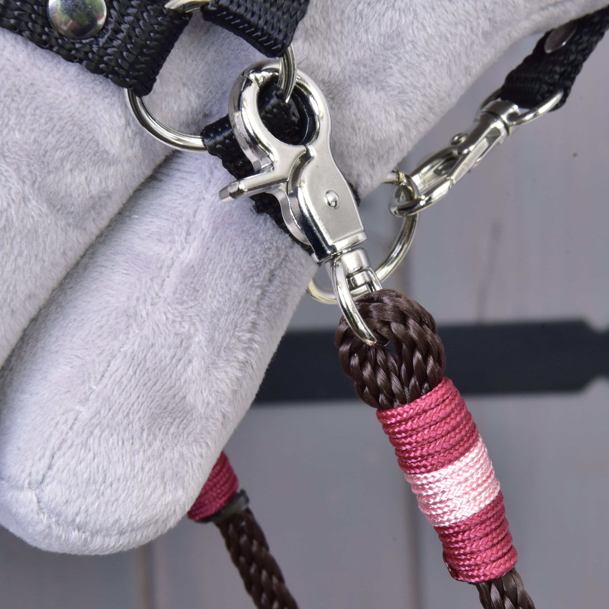 Bližnji posnetek karabina in roza-bordo ovoja temno rjavih vajeti York ob oglavki Hobby Horse konja