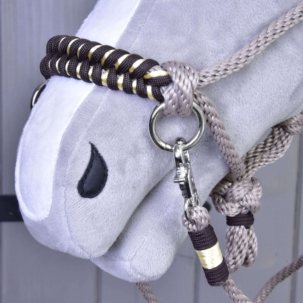 Bližnji posnetek pletenega nosnika v temno rjavi in zlati barvi, karabina in ovitega konca vajeti vrvičnega kompleta Splendid na Hobby Horse konju