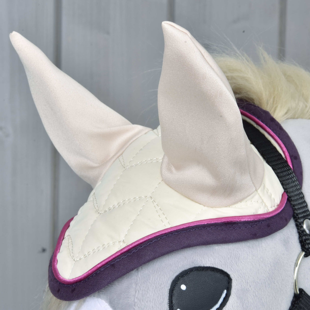 Close-up of the Set Supreme Crema ear bonnet with cream ears, cream quilting and a dark purple and pink edge