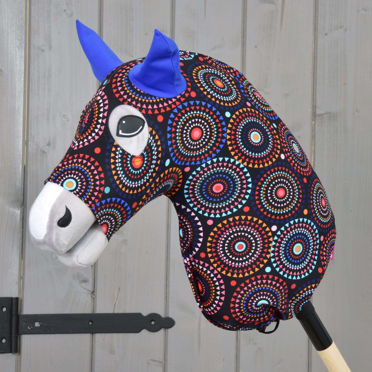 Hobby Horse zaščitna obleka Alice (Lycra) znamke LarDen, črna s pisanimi mandalami in kraljevsko modrimi ušesi, na sivem Hobby Horse konju
