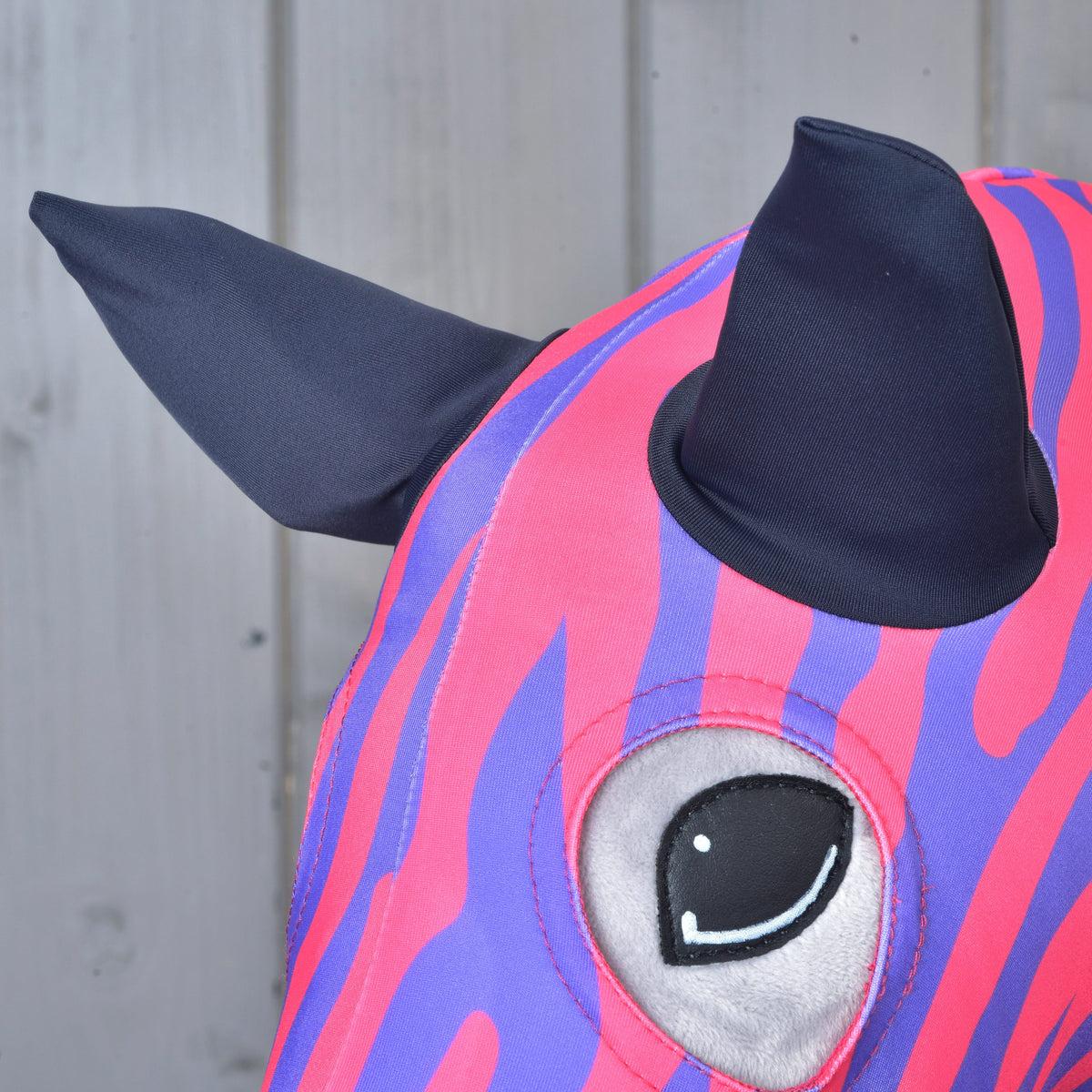 Bližnji posnetek Hobby Horse zaščitne obleke Fancy na plišasti glavi: temno modra ušesa iz blaga in odprtina za oko, obdana z zebrastimi progami