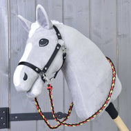 Svetlo siv Hobby Horse konj s črno oglavko in pletenimi črno-rdeče-rumenimi vajetmi Flag okoli vratu