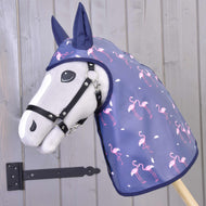 Siv Hobby Horse konj s črno oglavko, oblečen v modro-vijolično dežno pregrinjalo s potiskom roza flamingov in temno modrimi prevlekami za ušesa