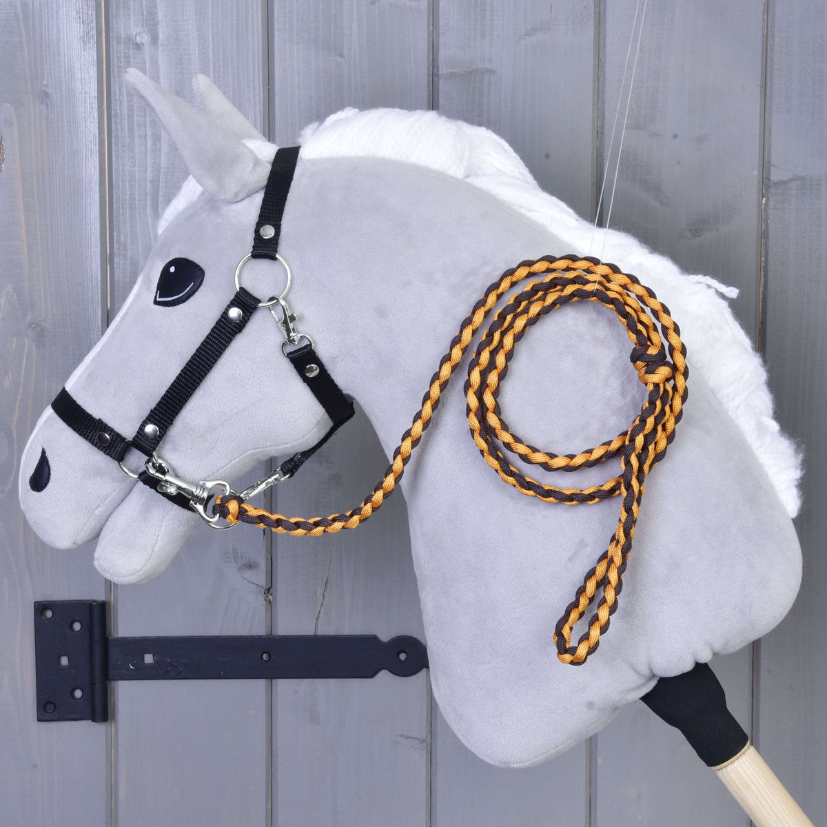 Oranžno-črn pleten povodec, pripet na črno oglavko sivega Hobby Horse konja z belo grivo