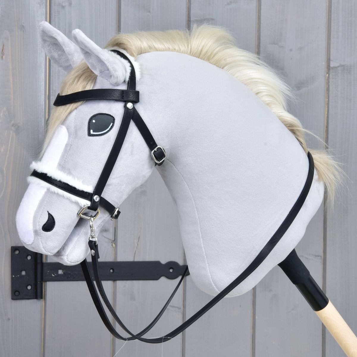 Hobby Horse kompletna uzda s krznom znamke LarDen, črna z belim krznenim nosnikom in vajetmi, na sivi plišasti glavi Hobby Horse konja