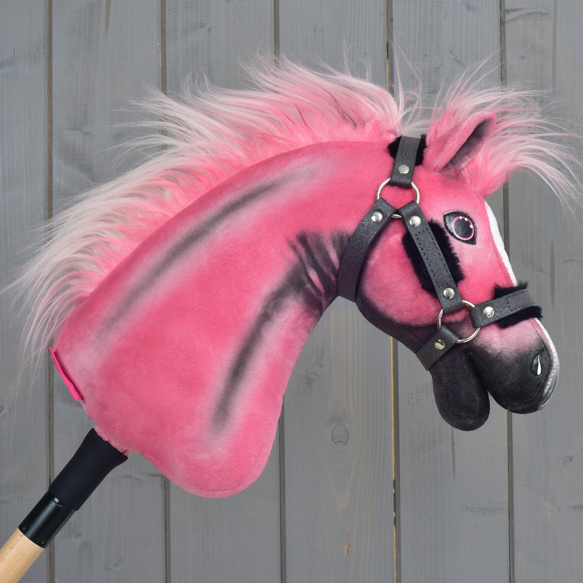 Hobby Horse Pinkie, obrnjen v desno: temno siva bleščeča oglavka, podložena s črnim krznom, in dolga roza griva, ki plapola nazaj