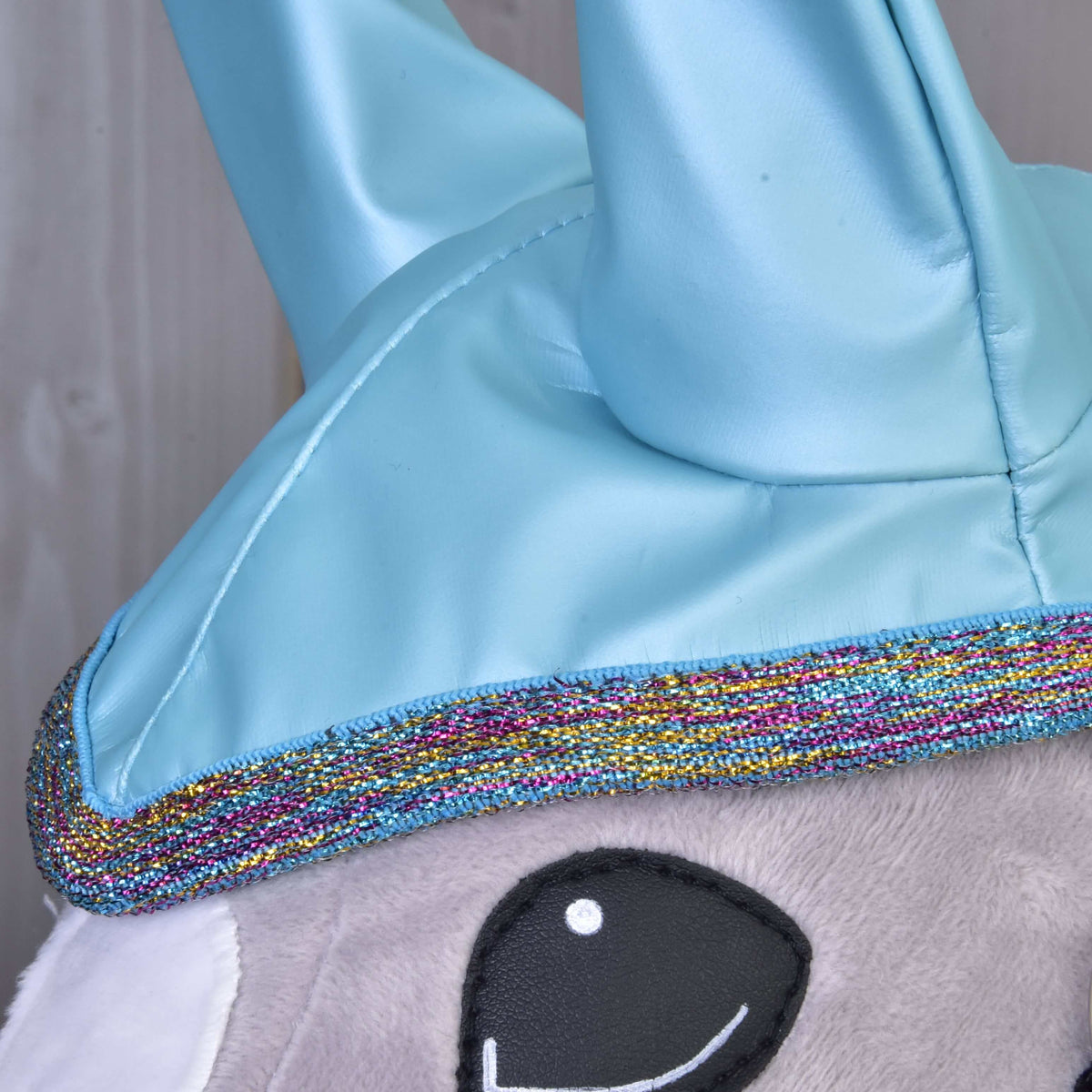 Bližnji posnetek roza, zlate in modre bleščeče obrobe pod svetlečimi ušesnimi deli Hobby Horse dežnega pregrinjala Light Blue