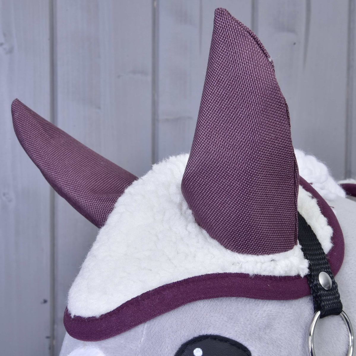 Close-up of the Set Loret ear bonnet with tall plum ears, fluffy cream sherpa and plum binding on a grey head