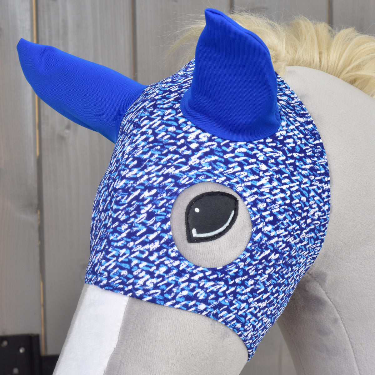 Close-up of the Horse Mask See on a grey Hobby Horse, the embroidered eye framed by the speckled blue fabric
