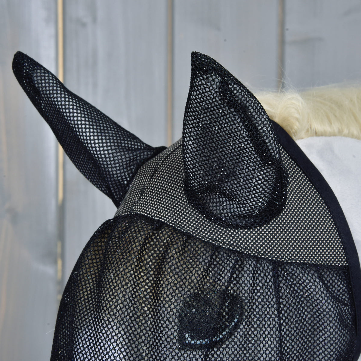 Pogled od strani na masko proti mrčesu s pokončnimi mrežastimi ušesi in fino črno mrežico čez oko svetlo sivega Hobby Horse konja