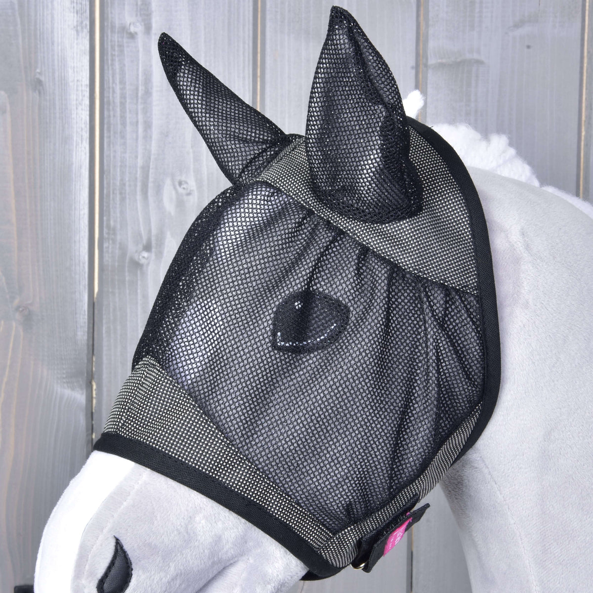 Bližnji posnetek Hobby Horse maske proti mrčesu De Luxe Grey na svetlo sivi glavi Hobby Horse konja: črna mrežasta ušesa, mrežica za oči in majhna roza etiketa
