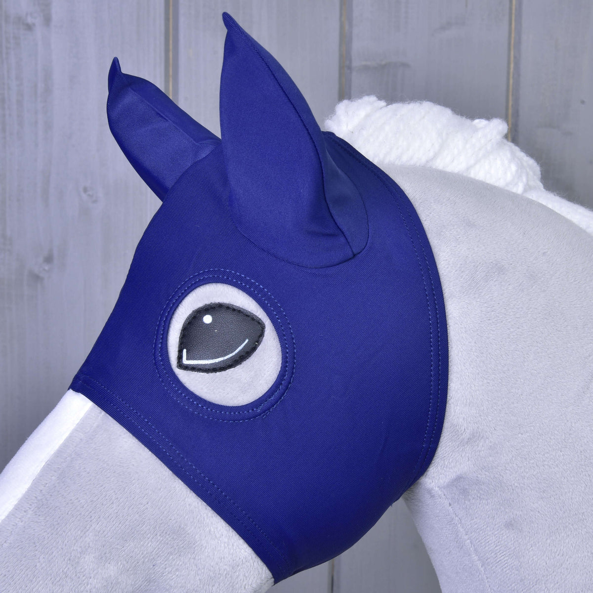 Bližnji posnetek maske s temno modrimi prevlekami za ušesa iz blaga na sivem Hobby Horse konju, črno oko obkroža odprtina