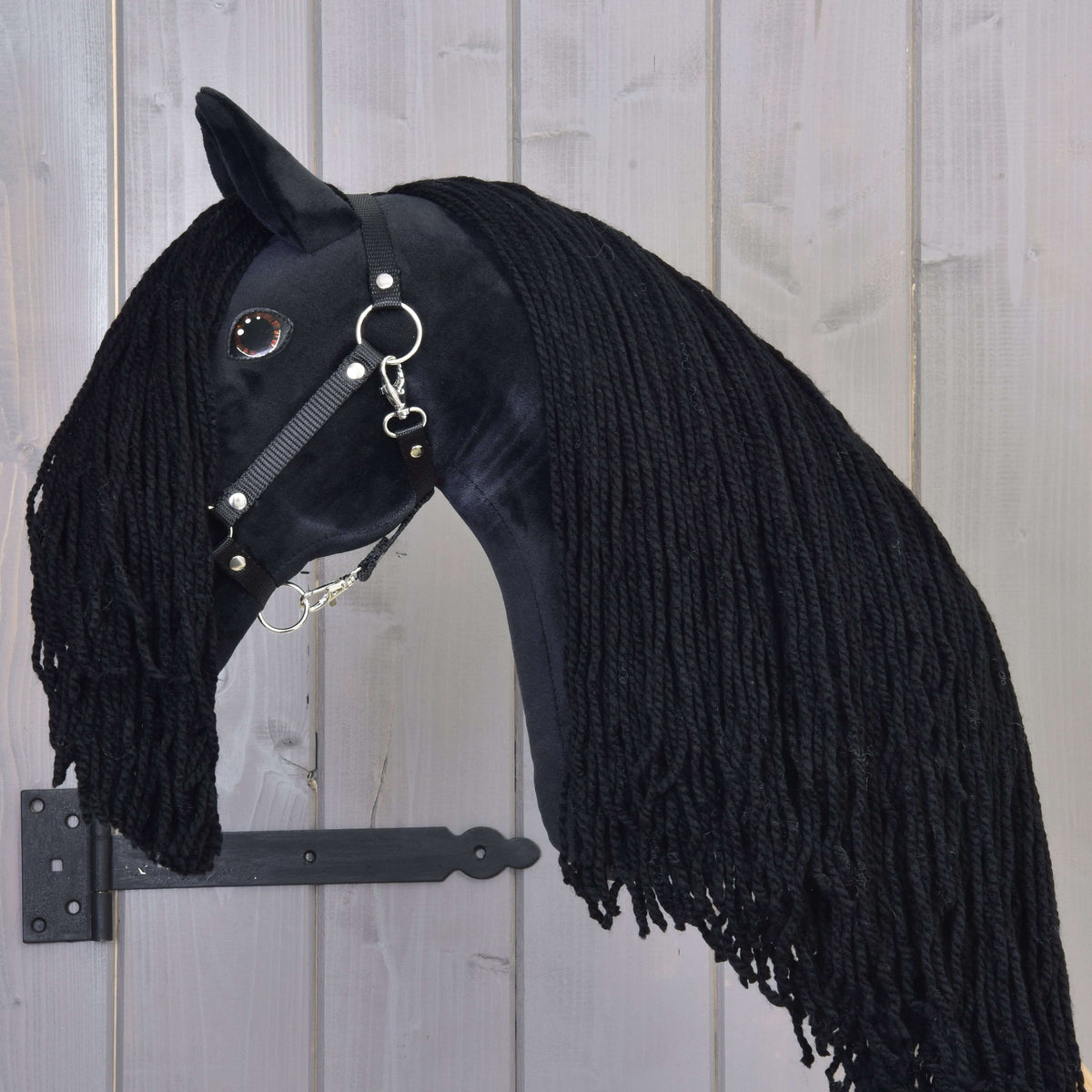 Black Hobby Horse with a long forelock falling past the cheek and a thick black yarn mane down the neck