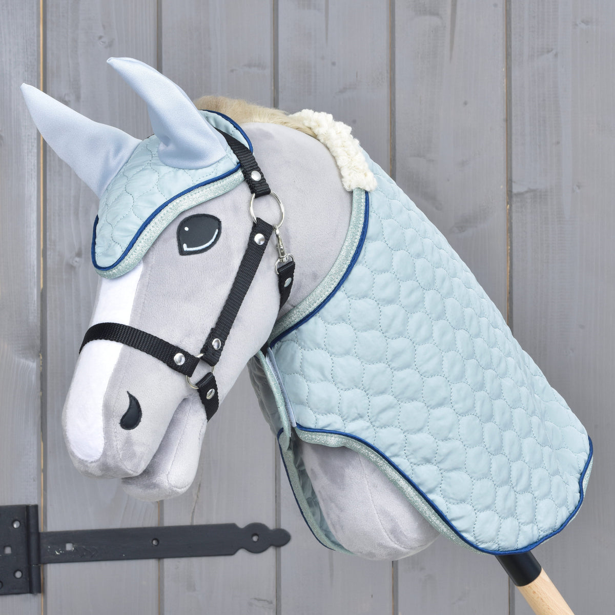 Grey Hobby Horse in a black halter wearing the Set Mint: pale blue quilted blanket and ear bonnet with navy piping