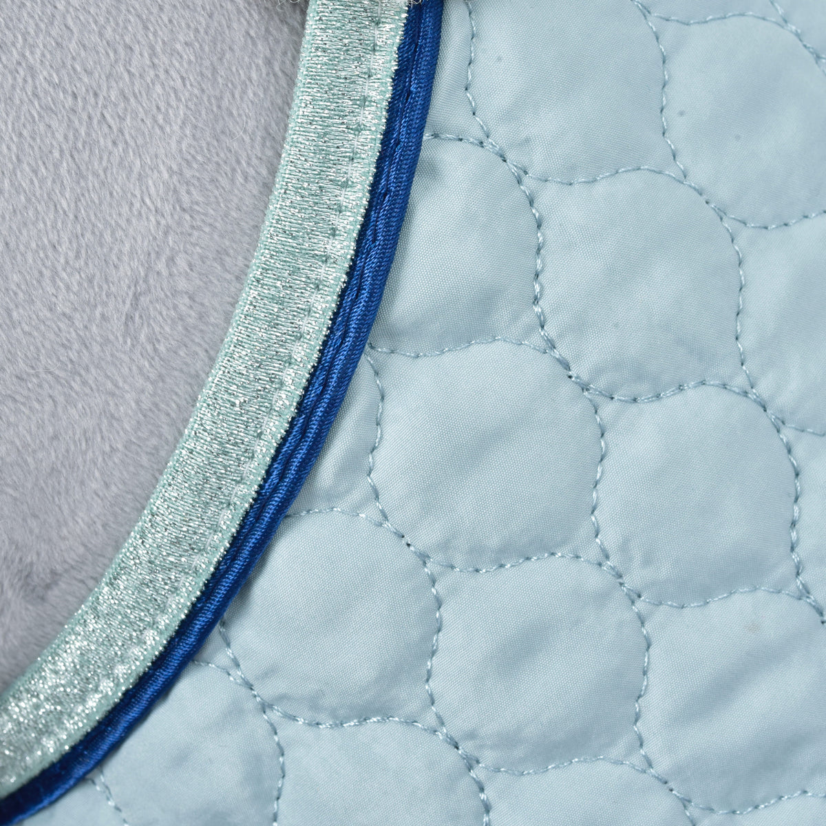 Macro of the rounded quilting, royal blue piping and mint glitter trim on the pale blue Hobby Horse Set Mint blanket